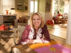 Melissa D-Arabian wearing a burgundy and white shirt while seated at a wooden table