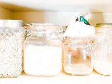 Shelf of glass storage jars in kitchen pantry.