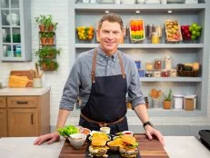 Bobby Flay posing with Burger 101, as seen on Food Network Kitchen Live.