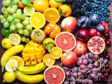 A colourful spectrum of fruit: oranges, lemons, limes, mandarins, grapes, plums, grapefruit, pomegranate, persimmons, bananas, cherries, apples, mangoes, blackberries and blueberries.