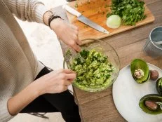 High angle of young woman making guacamole.