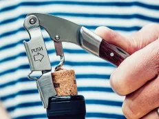 Close up of the removal of a cork from a wine bottle. The opener is the type which lifts the cork in two stages.