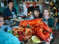 Family Having Christmas Dinner with Salmon Fish Fillet, Scallops, Lobster, Shrimps and Christmas Cake
