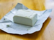 Close-up of a sack of open, cream cheese, on a white background. Shallow depth of focus.