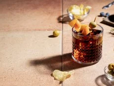 Vermouth cocktail with appetizer isolated on red background with copy space. Typical spanish appetizer.