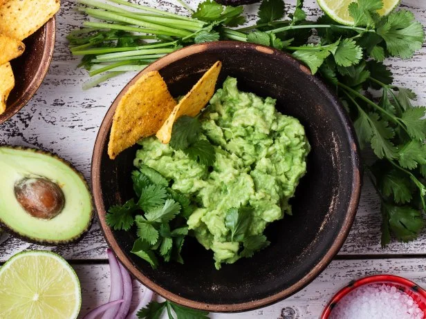 Making guacamole sauce, avocado, cilantro, lime, pepper, salt, tortilla corn chips. Mexican cuisine ingredients  on rustic wooden background, top view