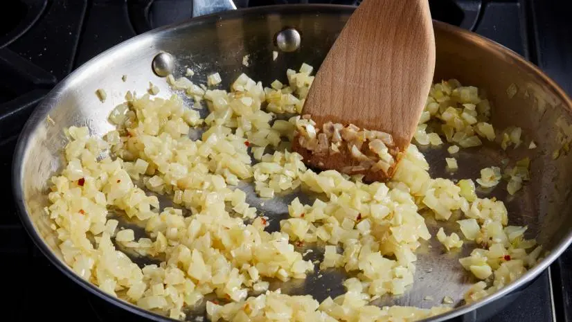 Photo showing the large skillet overhead with the cooked onions, garlic, crushed red pepper for Anne Burrell's Meatball recipe, as seen on Food Network.