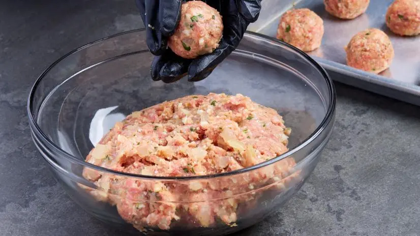 Photo showing gloved hands mixing a meatball for Anne Burrell's Meatball recipe, as seen on Food Network.