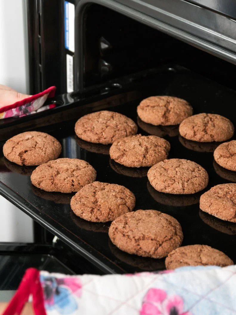 Woman getting roasting pan with oat cookies out of oven