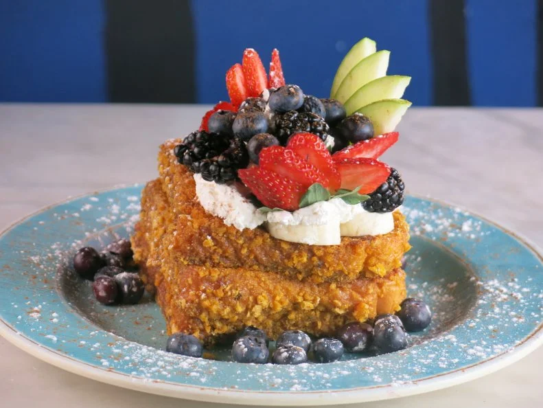The "Cereal-Encrusted French Toast" at Blue Moon Cafe in Baltimore, Maryland starts with thick slices of bread dredged in eggs and coated with crushed cereal. They're grilled on a flat top, then stacked high on a plate and topped with bananas, whipped cream, fresh berries, apple, cinnamon and powdered sugar, as seen on Travel Channel's Food Paradise.