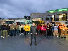 Nishaan, Fat Kid Food Co., Stop Drop N Roll, Rising Tiger, Good Fortune Company, Eat My Biscuits, Burger Walla, G’s Cheesesteaks and Cooking with Que team members in front of their trucks with host Tyler Florence, as seen on The Great Food Truck Race, Season 18.