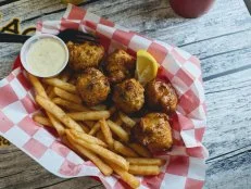 A basket of conch fritters and french fries served with dipping sauce